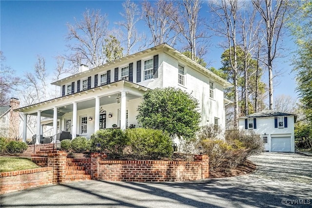 view of front facade featuring a porch, a chimney, and a garage