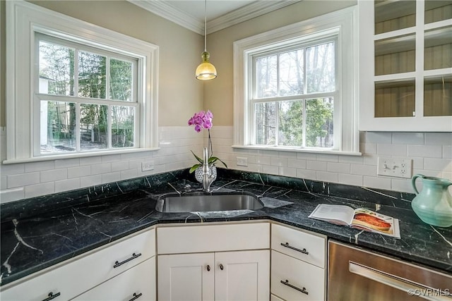 kitchen with ornamental molding, tasteful backsplash, stainless steel dishwasher, white cabinets, and hanging light fixtures