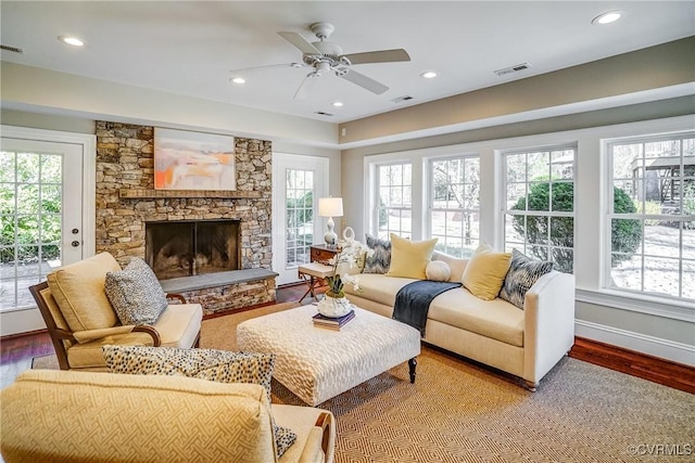 living area with a wealth of natural light, wood finished floors, and a fireplace