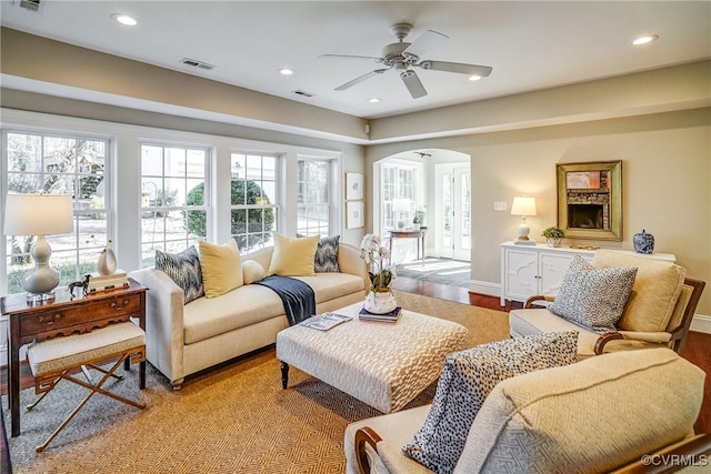 living area with arched walkways, visible vents, recessed lighting, and wood finished floors