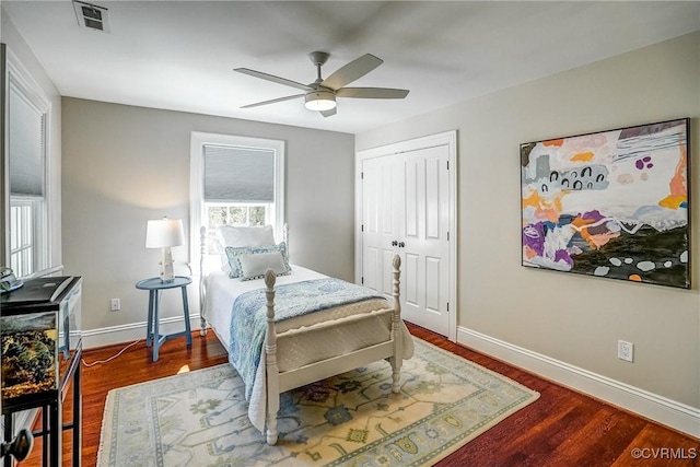 bedroom featuring wood finished floors, visible vents, baseboards, ceiling fan, and a closet