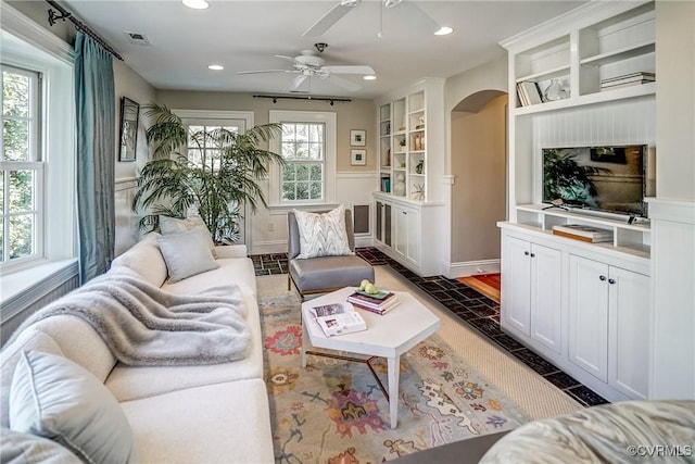 living room featuring arched walkways, built in features, recessed lighting, and visible vents