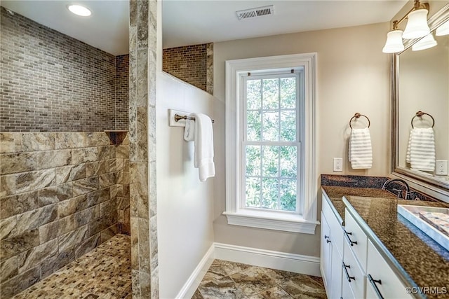 bathroom featuring visible vents, plenty of natural light, a walk in shower, and vanity