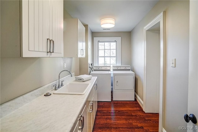 clothes washing area with visible vents, washing machine and dryer, dark wood-style floors, cabinet space, and a sink