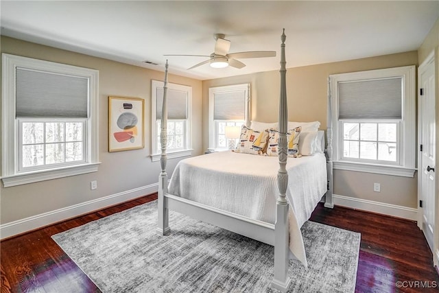 bedroom featuring multiple windows, wood finished floors, and baseboards