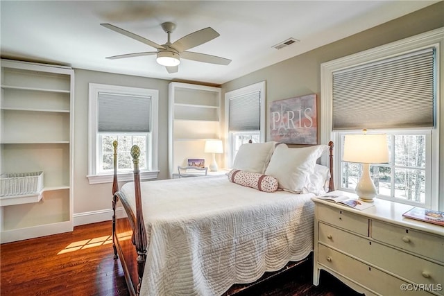 bedroom with multiple windows, wood finished floors, visible vents, and baseboards