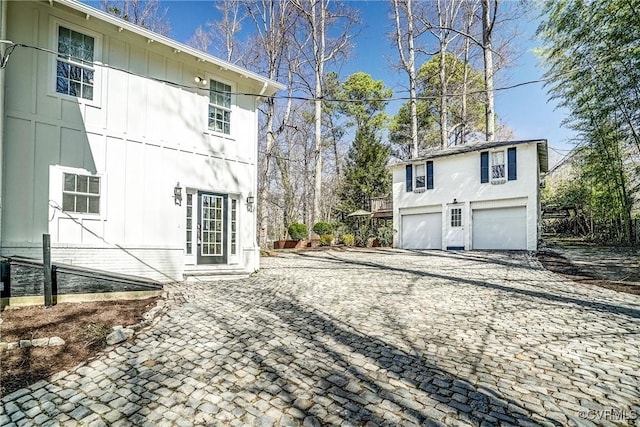 view of side of property with board and batten siding, an attached garage, and decorative driveway