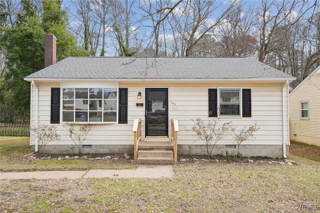 view of front of house with crawl space, a shingled roof, a chimney, and a front yard