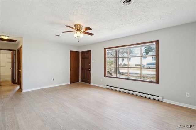 spare room with light wood-style flooring, a baseboard radiator, visible vents, and baseboards