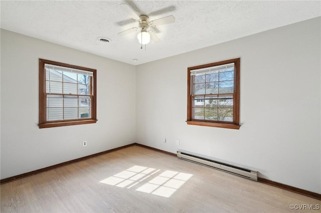 spare room featuring a textured ceiling, a baseboard radiator, visible vents, baseboards, and light wood-type flooring