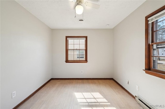 unfurnished room with visible vents, a baseboard heating unit, light wood-style floors, ceiling fan, and baseboards