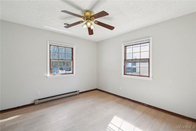 unfurnished room featuring light wood-style floors, a baseboard radiator, a healthy amount of sunlight, and a textured ceiling