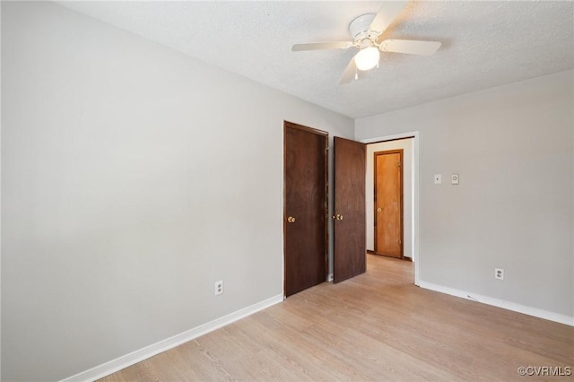 spare room featuring a textured ceiling, light wood-style flooring, and baseboards