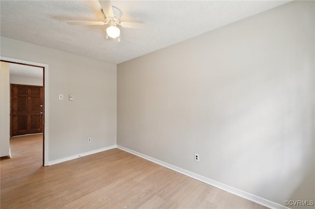 empty room with a ceiling fan, baseboards, a textured ceiling, and light wood finished floors