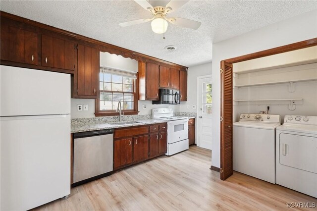 kitchen with white appliances, light wood finished floors, visible vents, washer and dryer, and a sink