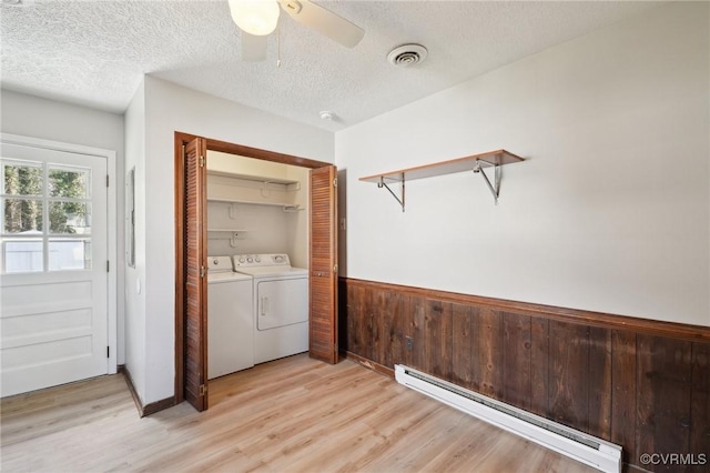 washroom featuring a baseboard heating unit, laundry area, visible vents, washer and dryer, and wainscoting