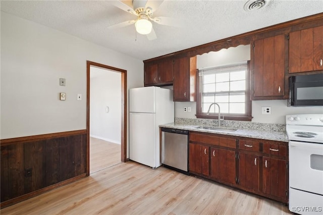 kitchen featuring a textured ceiling, white appliances, a sink, visible vents, and light wood-type flooring