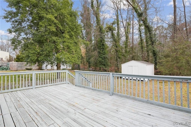 wooden deck featuring an outdoor structure, a storage shed, and fence