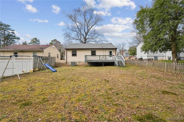 rear view of house with a playground, a lawn, a fenced backyard, and a wooden deck