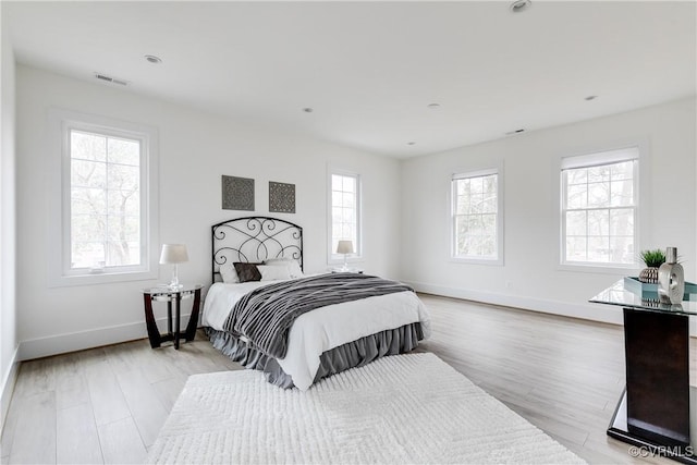 bedroom featuring light wood finished floors, baseboards, and visible vents