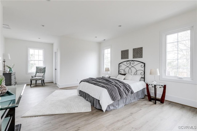 bedroom with multiple windows, visible vents, and wood finished floors