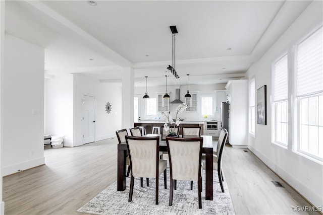 dining area with light wood finished floors, visible vents, and baseboards