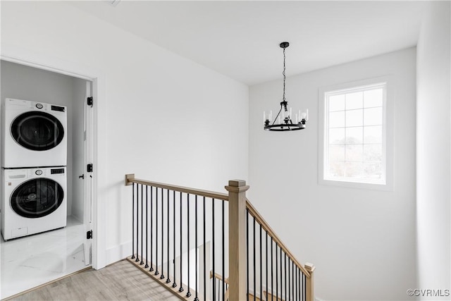 laundry area featuring a chandelier, laundry area, marble finish floor, and stacked washer / drying machine