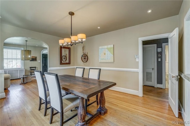 dining space with arched walkways, light wood-style flooring, recessed lighting, a notable chandelier, and baseboards