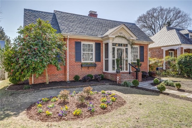 view of front of home featuring brick siding, a chimney, and a shingled roof