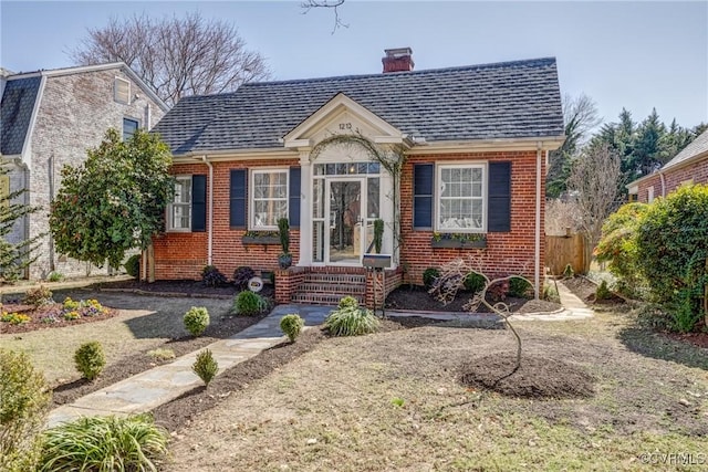 bungalow-style house featuring brick siding, a chimney, and roof with shingles