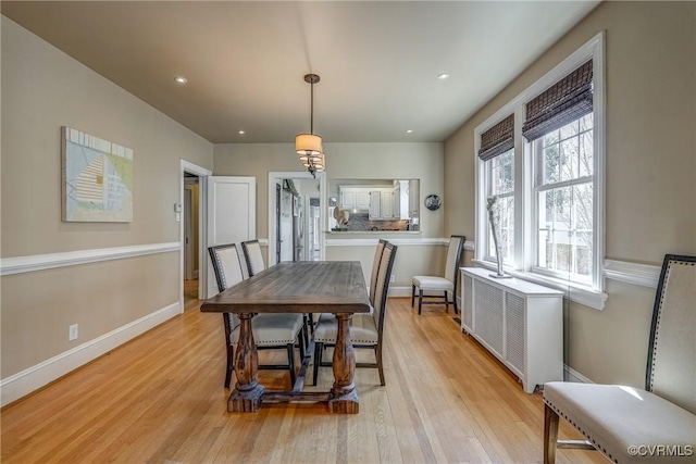 dining room with light wood-style floors, radiator heating unit, baseboards, and recessed lighting