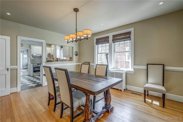 dining room with baseboards, visible vents, radiator, light wood-style flooring, and a notable chandelier