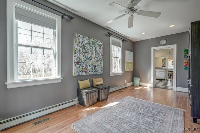 living area with a baseboard radiator, recessed lighting, baseboards, and wood finished floors