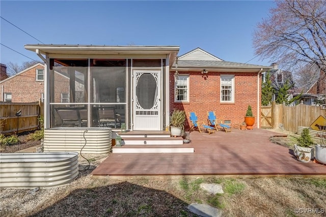 rear view of property with brick siding, crawl space, fence, and a sunroom