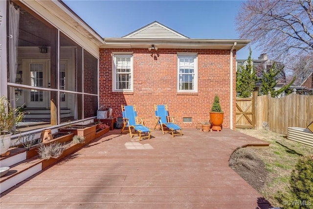 exterior space with brick siding, a sunroom, crawl space, fence, and a wooden deck