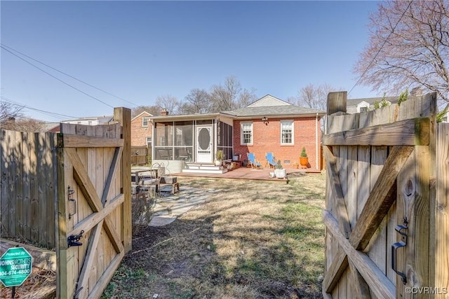 rear view of property with brick siding, a patio, a sunroom, crawl space, and fence