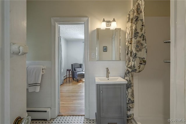 bathroom featuring a wainscoted wall, baseboard heating, vanity, and tile walls