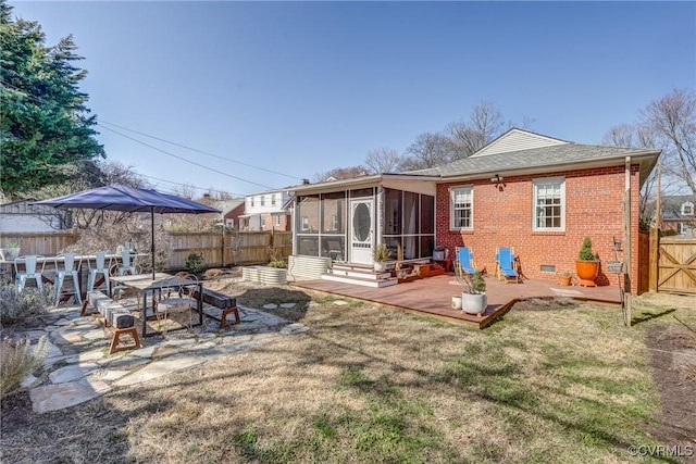 rear view of house with brick siding, a lawn, a sunroom, crawl space, and a fenced backyard