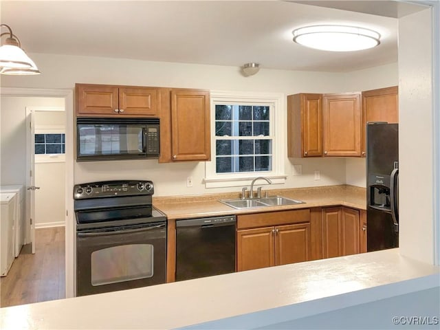 605 Conley Rd, Richmond, VA 23227 - kitchen featuring brown cabinetry, washing machine and clothes dryer, light countertops, black appliances, and a sink