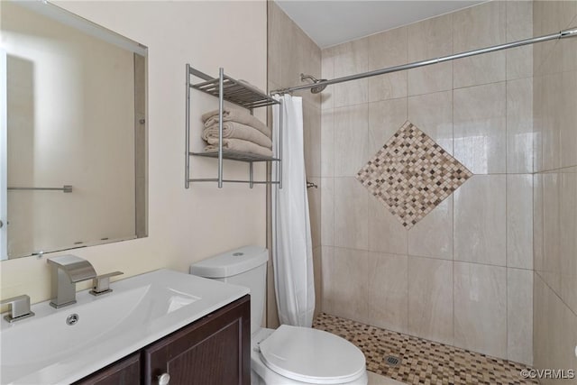 bathroom featuring toilet, tiled shower, and vanity