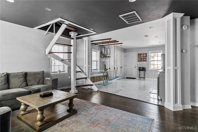 living area featuring baseboards, visible vents, ornate columns, and wood finished floors