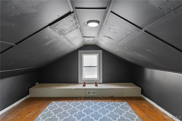 bonus room with wood-type flooring, visible vents, vaulted ceiling, and baseboards