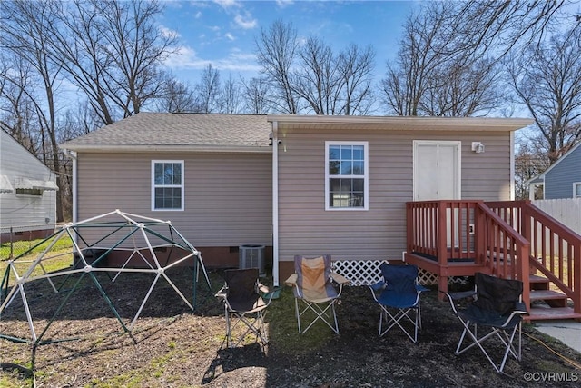 rear view of house featuring cooling unit, roof with shingles, and fence