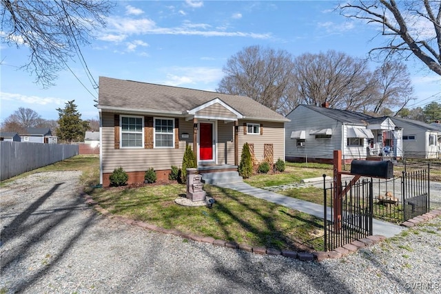 bungalow featuring driveway, a shingled roof, fence, and a front yard