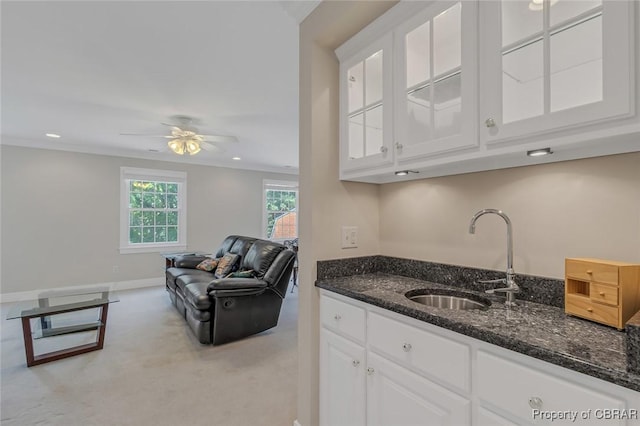 kitchen with dark stone countertops, a sink, and white cabinets