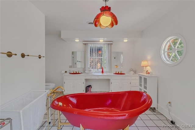 full bath featuring tile patterned flooring, a freestanding tub, and a healthy amount of sunlight