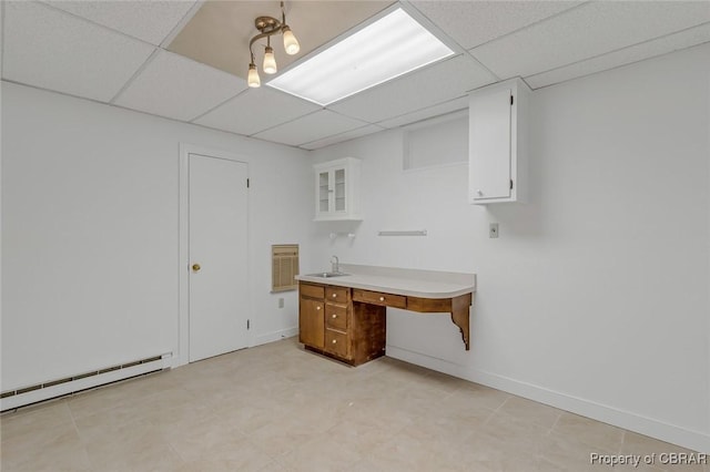 unfurnished office featuring a baseboard heating unit, a paneled ceiling, a sink, and baseboards