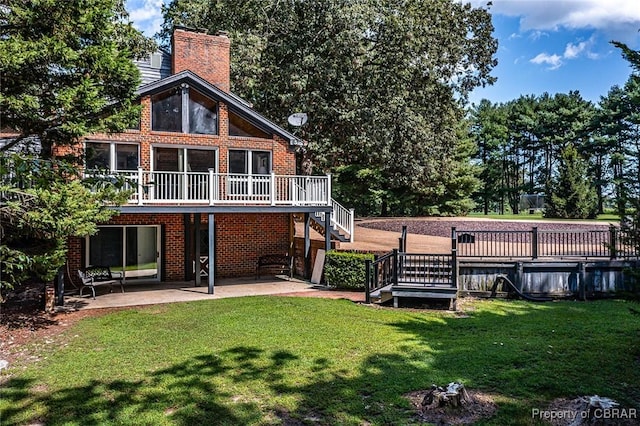 rear view of property featuring a lawn, a patio, a chimney, stairway, and a wooden deck