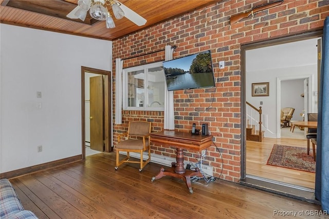 home office with baseboards, a ceiling fan, wooden ceiling, hardwood / wood-style flooring, and brick wall