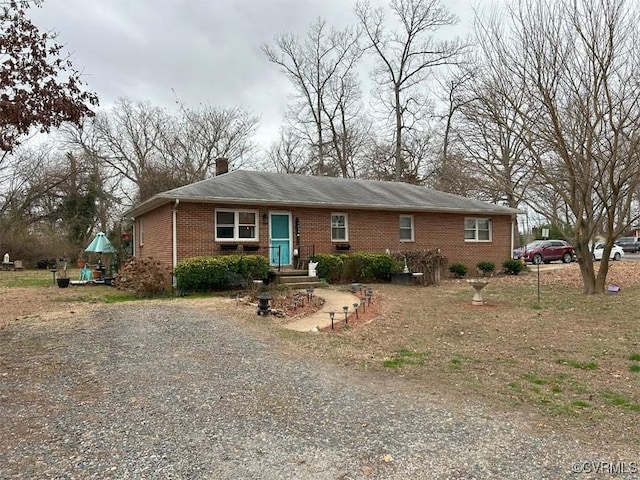 ranch-style home featuring brick siding, driveway, and a chimney